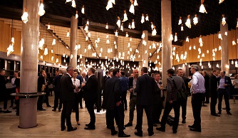 Picture of our main foyer at night. Our copper wire lights are hanging from the ceiling and providing the light. The foyer is filled with people standing and chatting.
